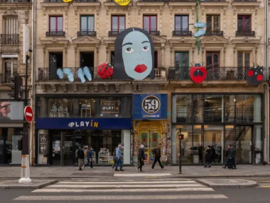 Façade d'immeuble parisien ornée de décorations artistiques, avec des passants sur le trottoir.