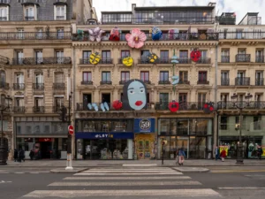 Façade d'immeuble parisien ornée de grandes décorations colorées, dont un visage et des coccinelles.