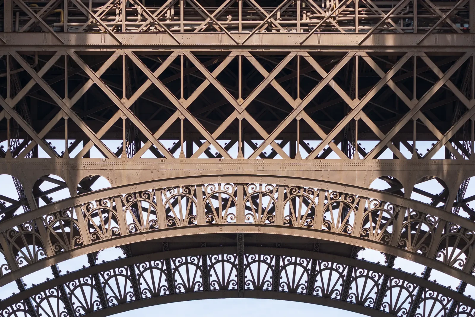 Détail architectural de la Tour Eiffel, montrant sa structure métallique complexe et ses arches décoratives.
