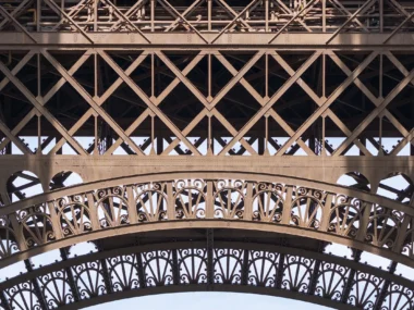 Détail architectural de la Tour Eiffel, montrant sa structure métallique complexe et ses arches décoratives.
