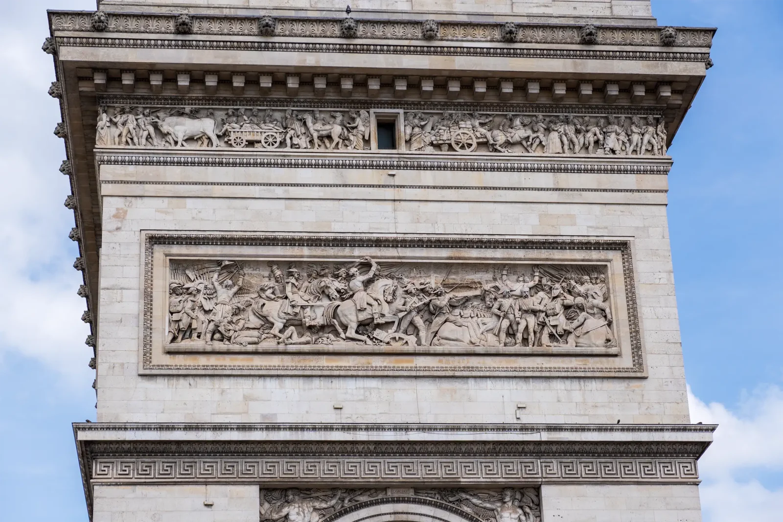 Détail d'une façade en pierre de l'Arc de Triomphe, ornée de frises sculptées.