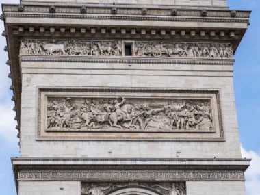 Détail d'une façade en pierre de l'Arc de Triomphe, ornée de frises sculptées.