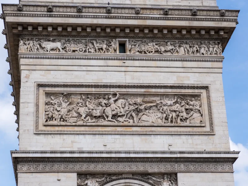 Détail d'une façade en pierre de l'Arc de Triomphe, ornée de frises sculptées.