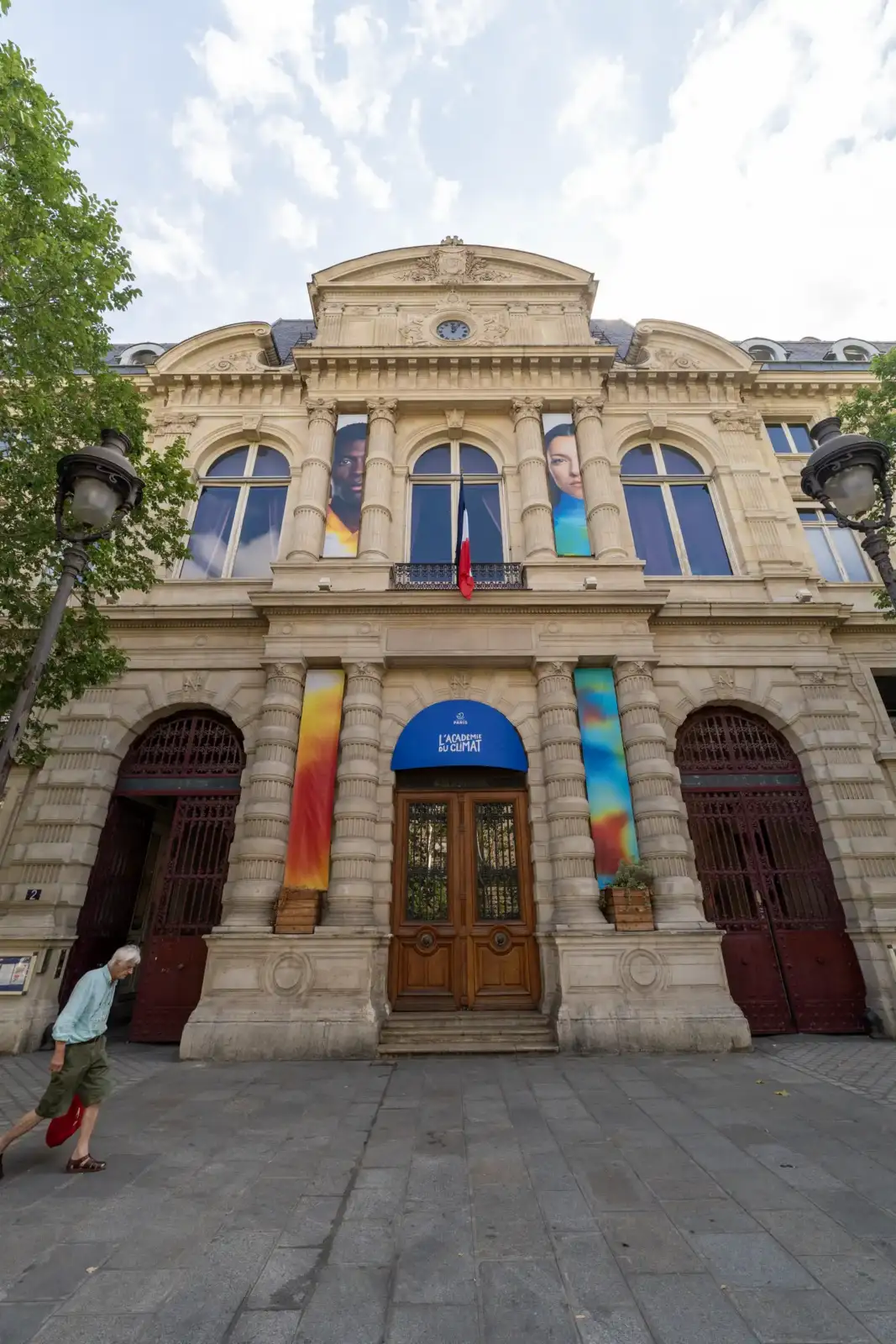 Façade classique de l'Académie du Climat à Paris sous un ciel nuageux.