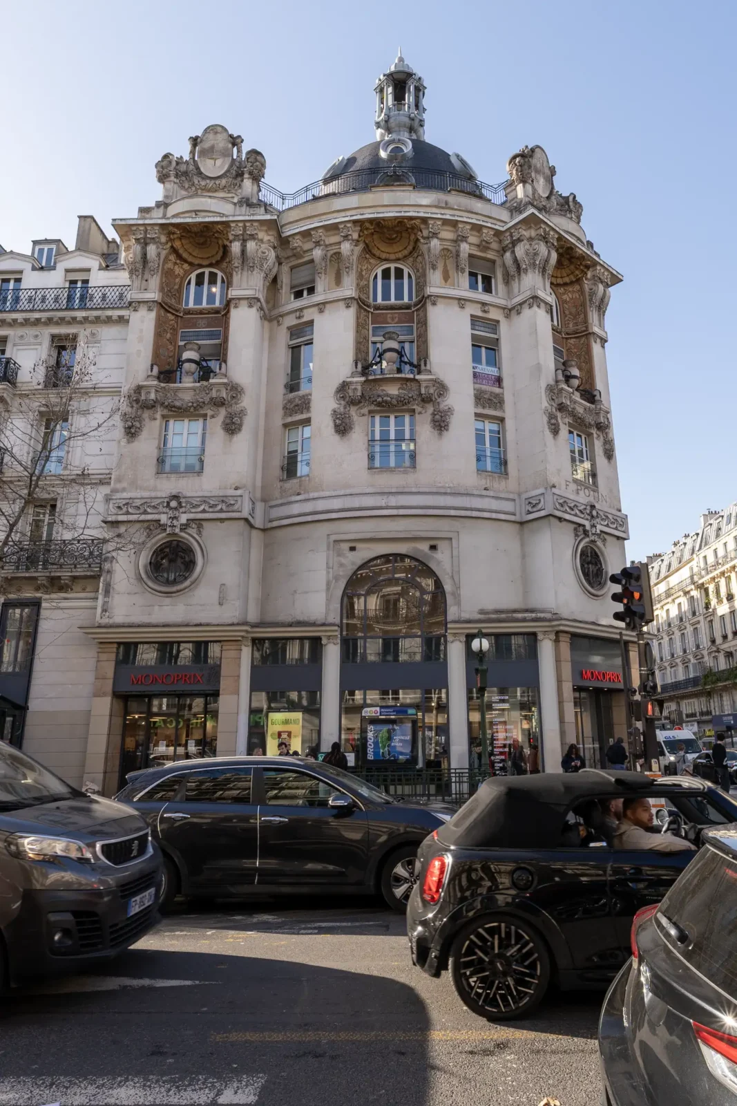 La façade sculptée de l'ancien magasin Félix Potin surplombe une rue parisienne animée.