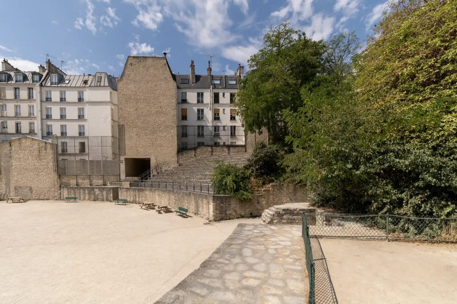 Vue intérieure des Arènes de Lutèce bordées par des immeubles haussmanniens à Paris.