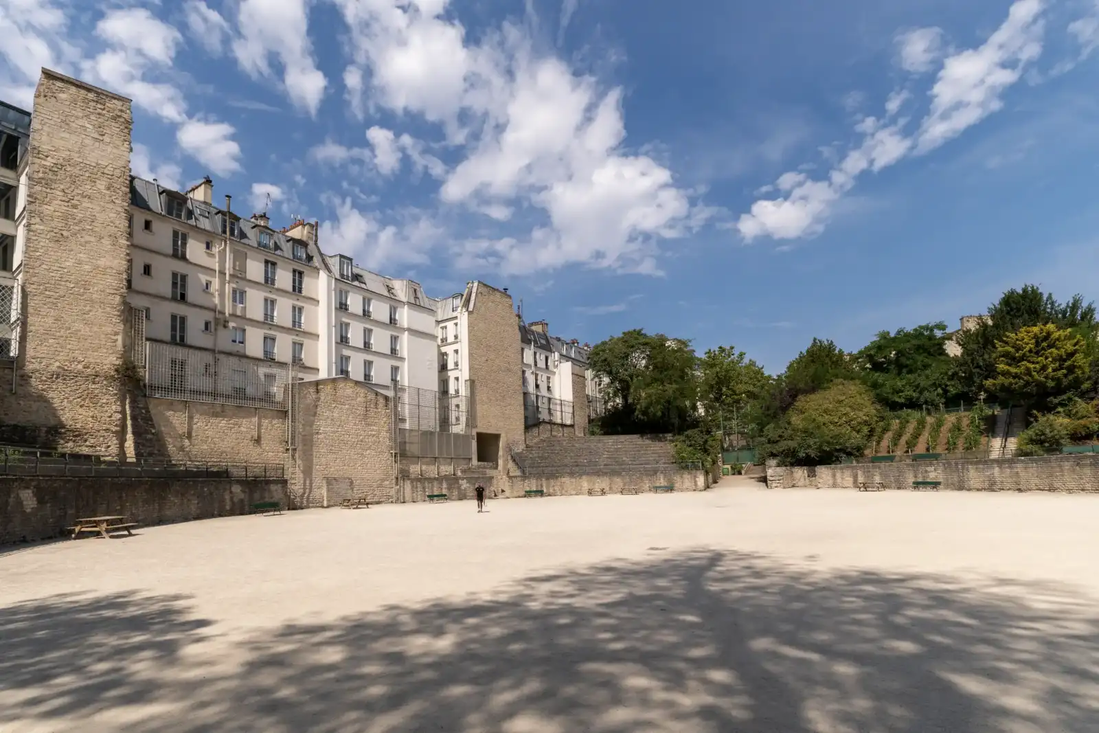 Vue panoramique des Arènes de Lutèce à Paris, encadrées par des immeubles et des arbres.