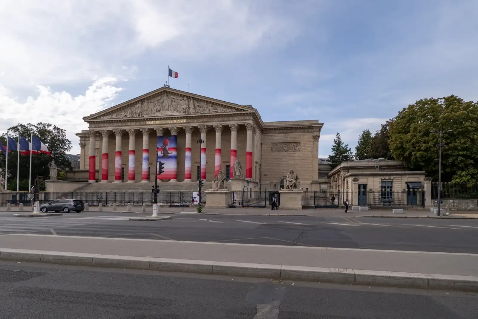 Façade monumentale de l'Assemblée nationale à Paris décorée de bandes colorées pour une exposition.