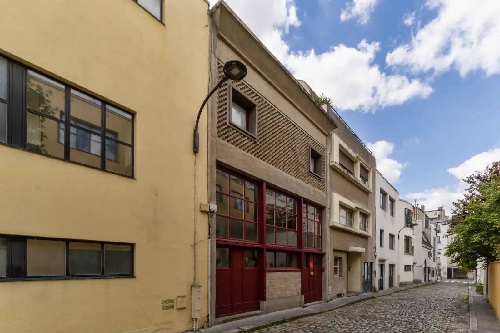 Vue de la rue pavée des anciens ateliers parisiens de Chana Orloff sous un ciel bleu.
