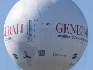 Le ballon captif Generali blanc flotte dans le ciel bleu, affichant des graphiques climatiques.