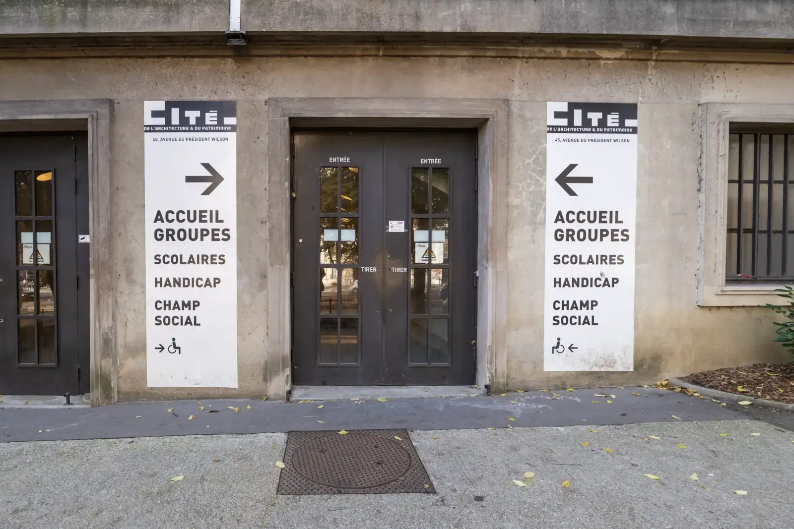 La façade grise de la Cité de l’architecture avec de grandes affiches informatives.