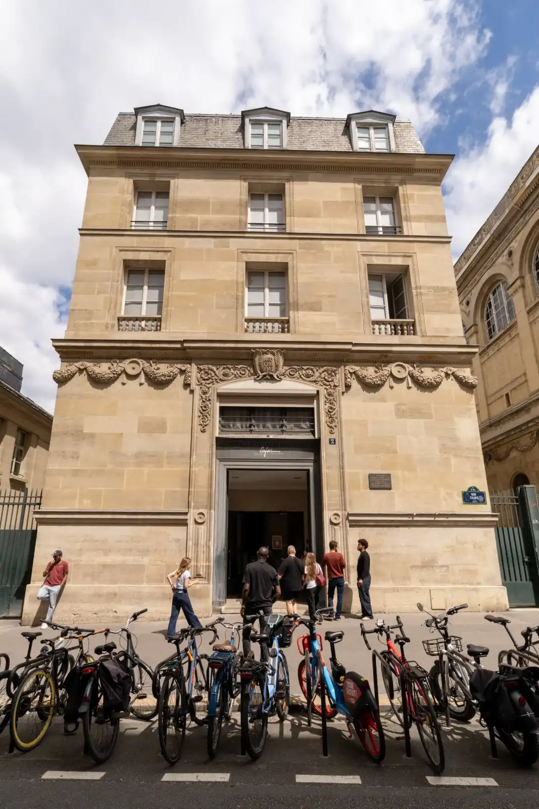 Façade en pierre claire de la bibliothèque Cujas à Paris avec des vélos garés devant.