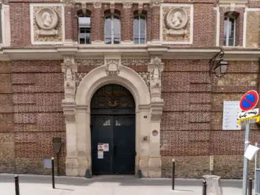 Entrée principale en pierre et briques de la bibliothèque Sainte-Barbe à Paris.
