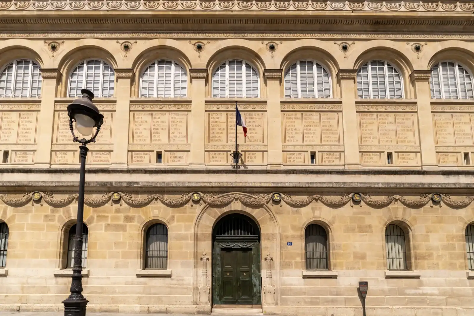 La façade beige de la bibliothèque Sainte-Geneviève présente des fenêtres cintrées et de nombreux noms inscrits.