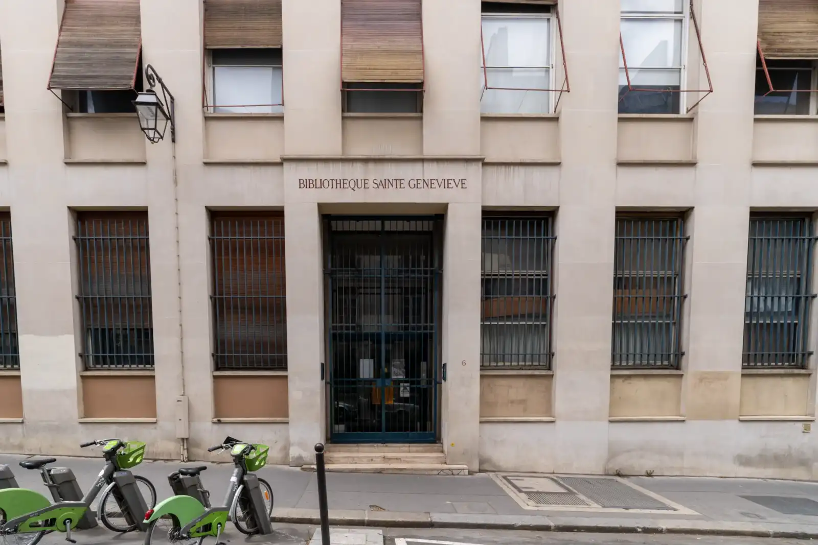 Façade en pierre de la bibliothèque Sainte-Geneviève à Paris avec des vélos garés.