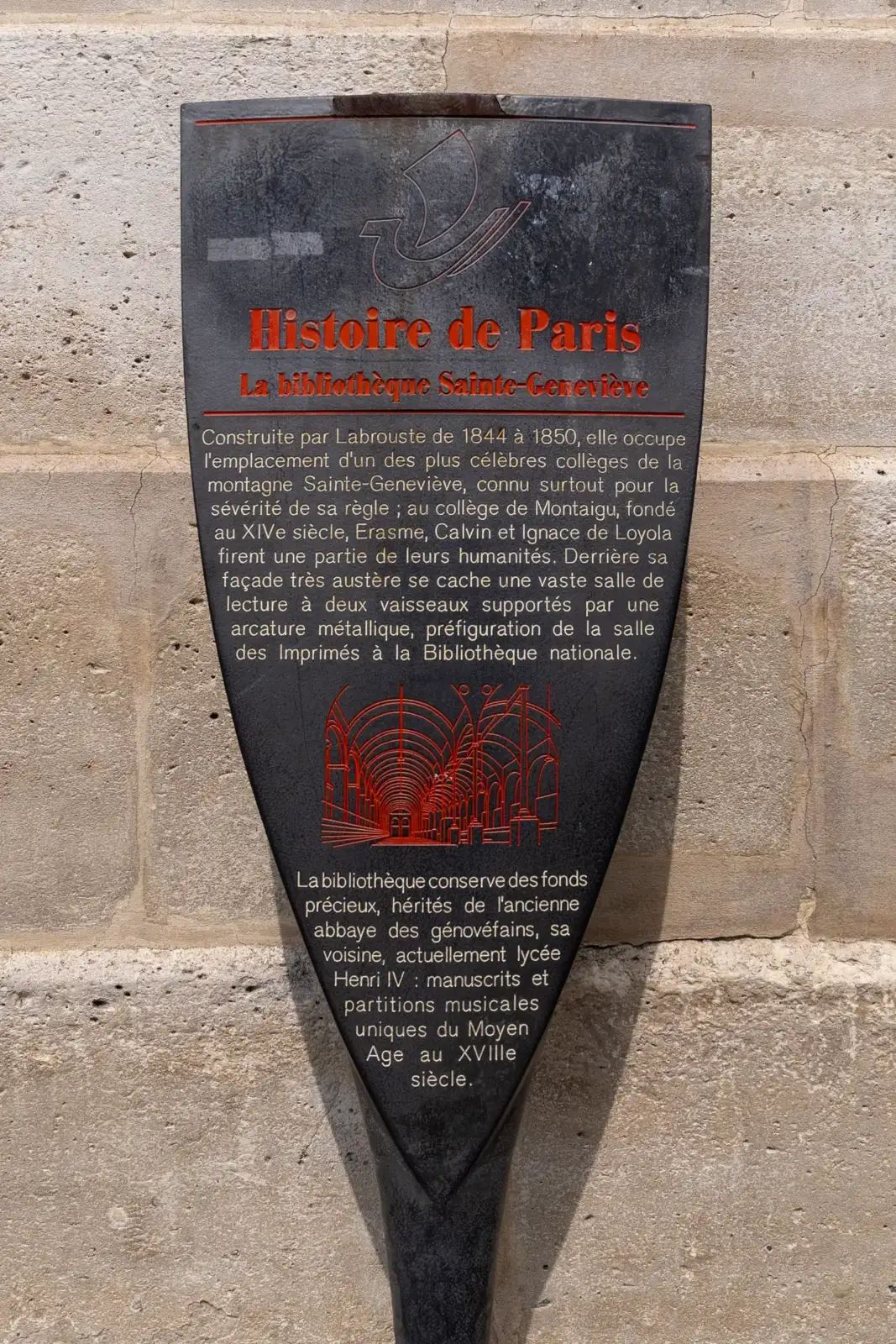 Un panneau historique noir fixé sur un mur en pierre de Paris.
