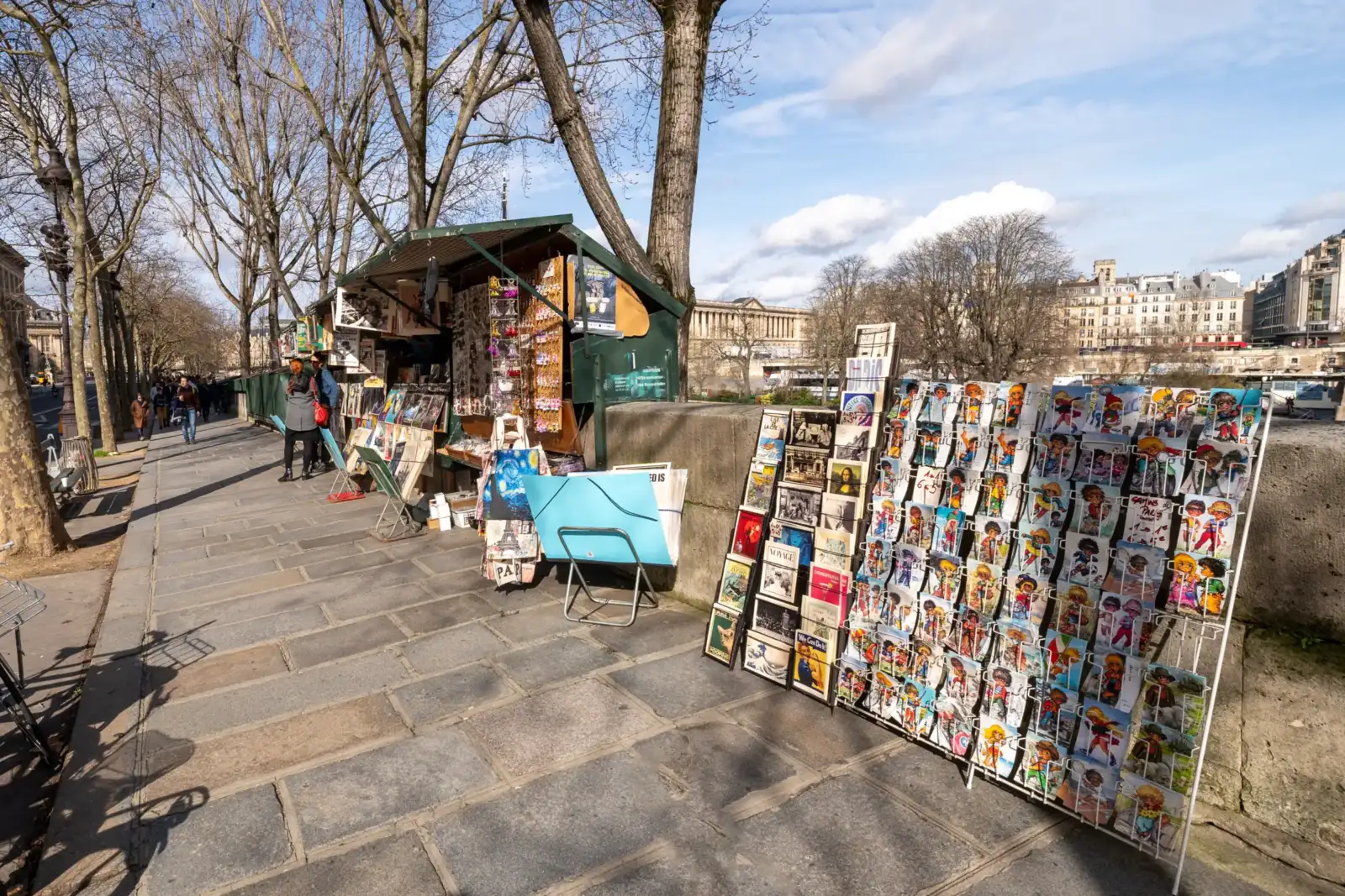 Un bouquiniste parisien expose des cartes postales colorées le long des quais de Seine.