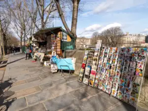 Un bouquiniste parisien expose des cartes postales colorées le long des quais de Seine.