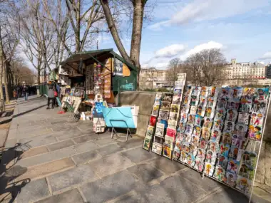 Un bouquiniste parisien expose des cartes postales colorées le long des quais de Seine.