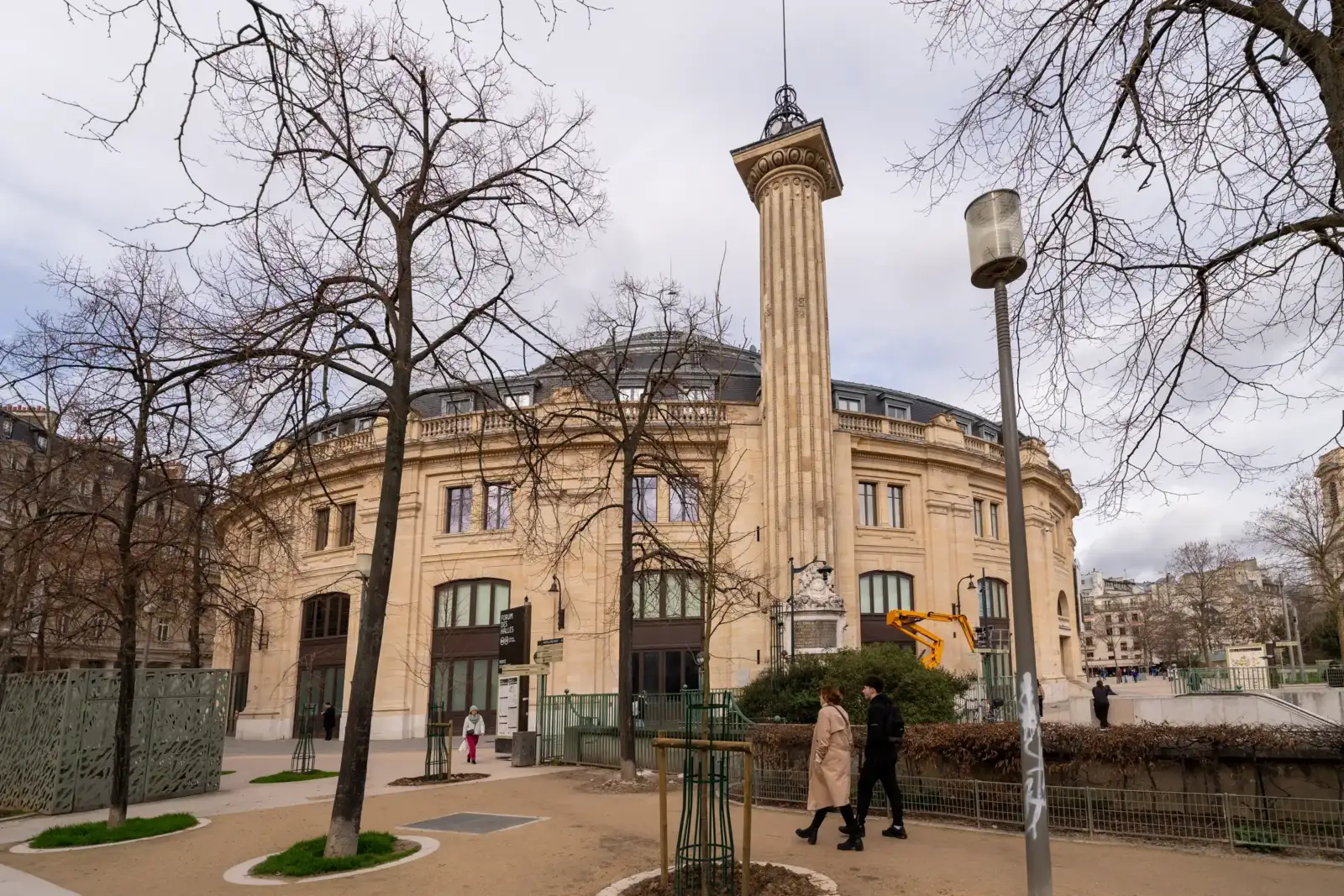 La Bourse de Commerce à Paris avec sa colonne historique entourée d'arbres dénudés.