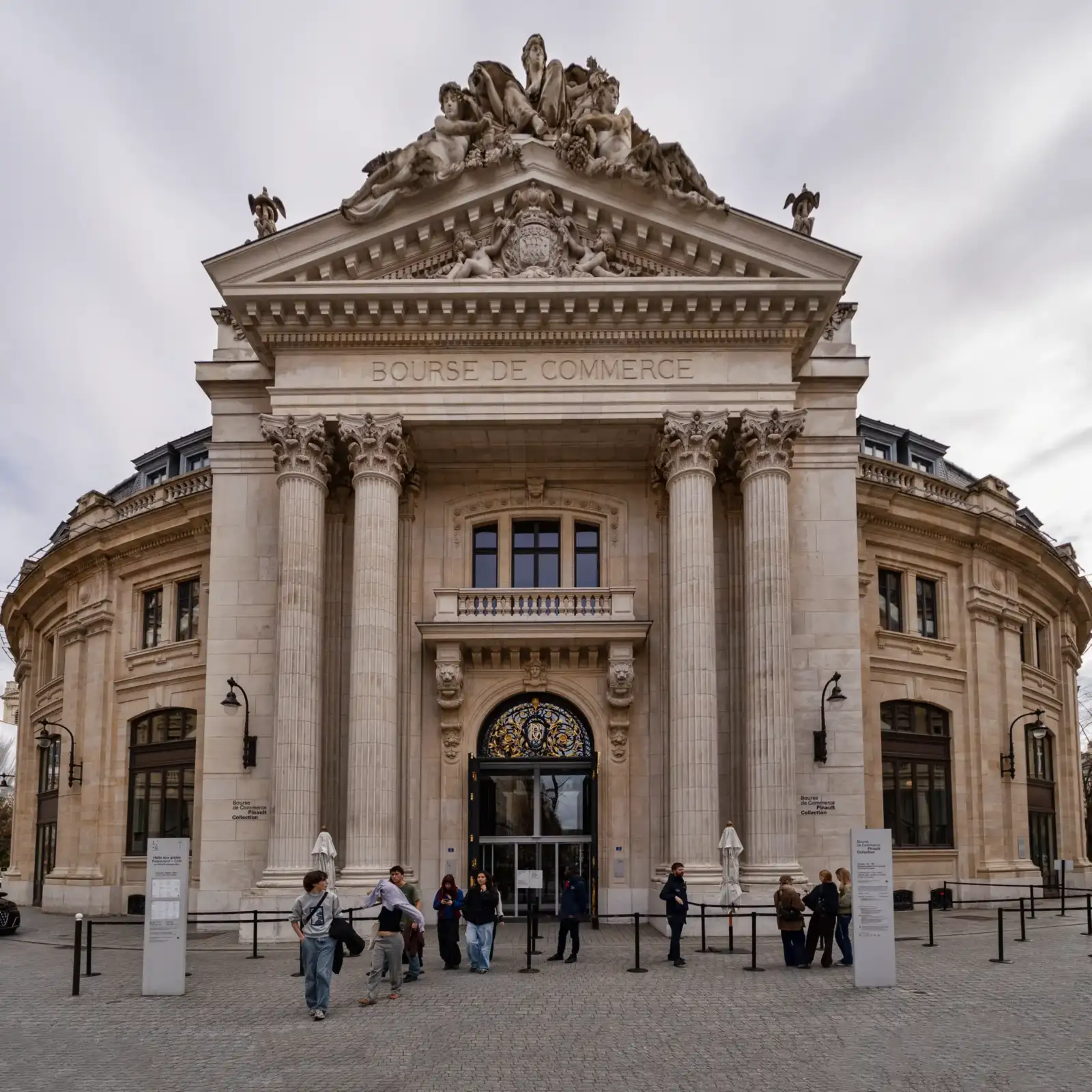 Façade monumentale de la Bourse de Commerce à Paris avec des visiteurs devant l'entrée.