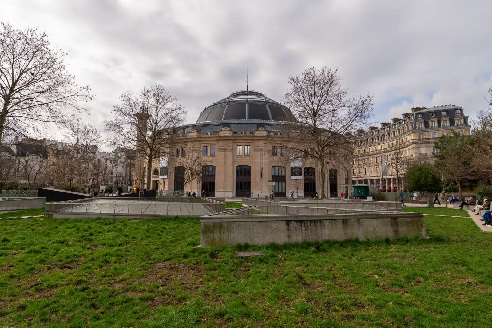 La Bourse de Commerce avec son dôme imposant domine un jardin urbain à Paris.