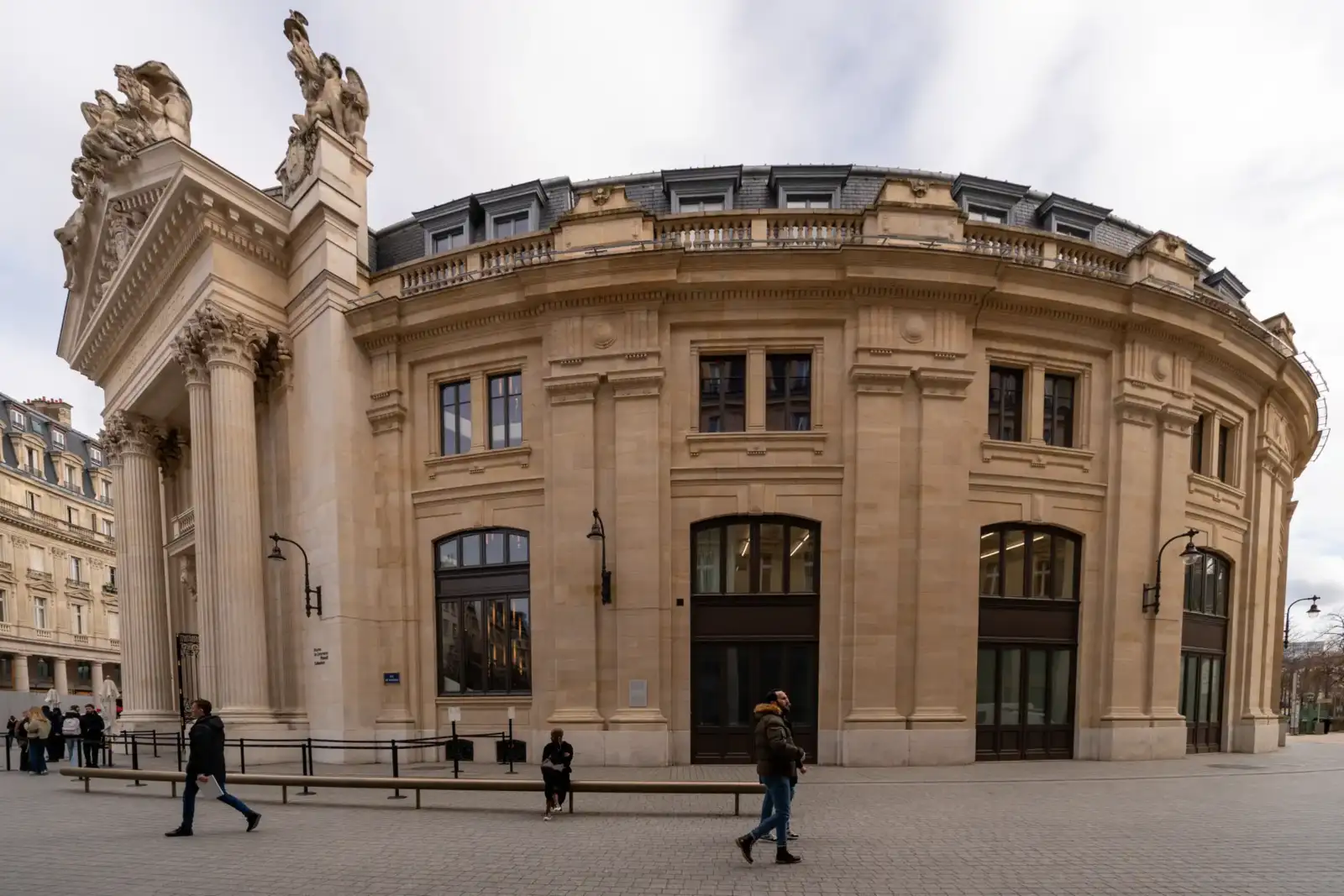 La façade arrondie de la Bourse de Commerce à Paris sous un ciel nuageux.