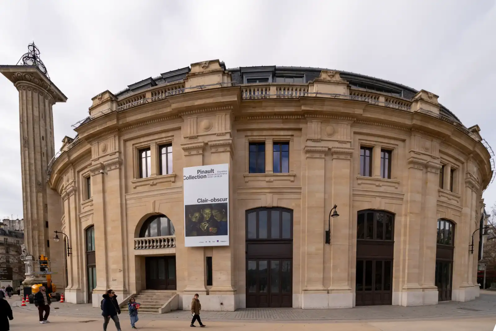 La façade arrondie de la Bourse de Commerce à Paris avec une affiche publicitaire.