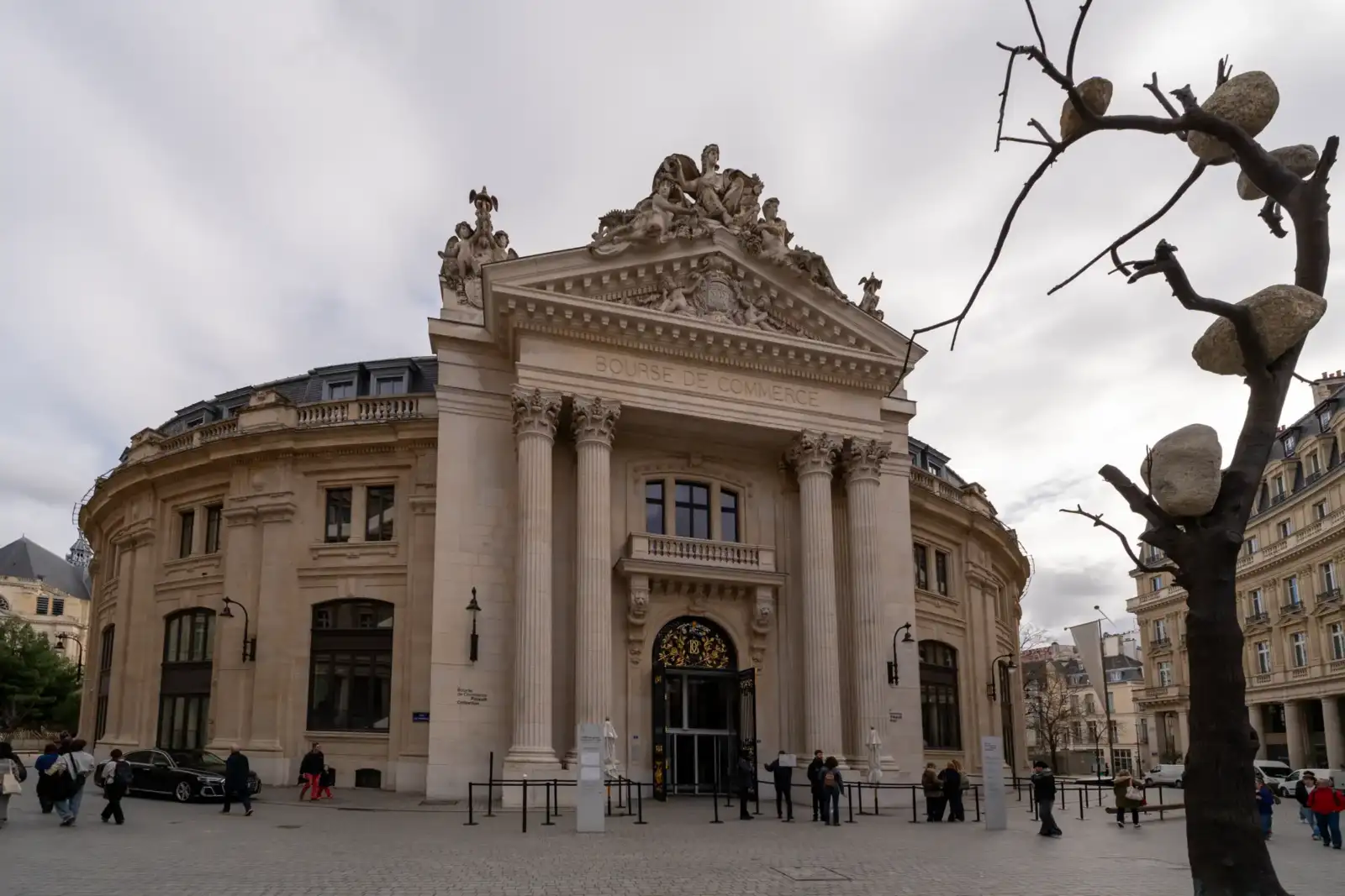 La façade néoclassique de la Bourse de Commerce à Paris sous un ciel nuageux.