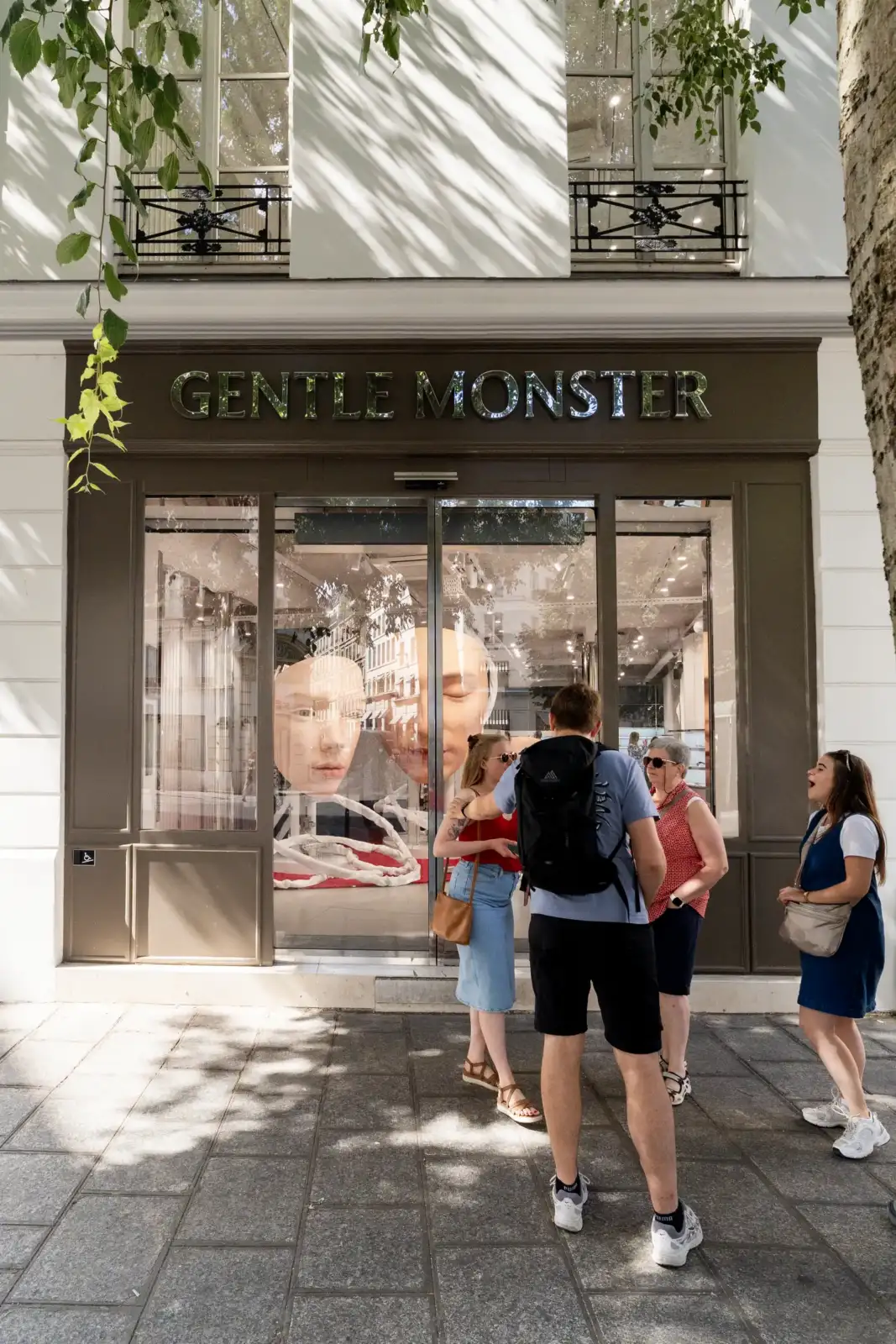 Quatre personnes regardent la vitrine de la boutique Gentle Monster à Paris.