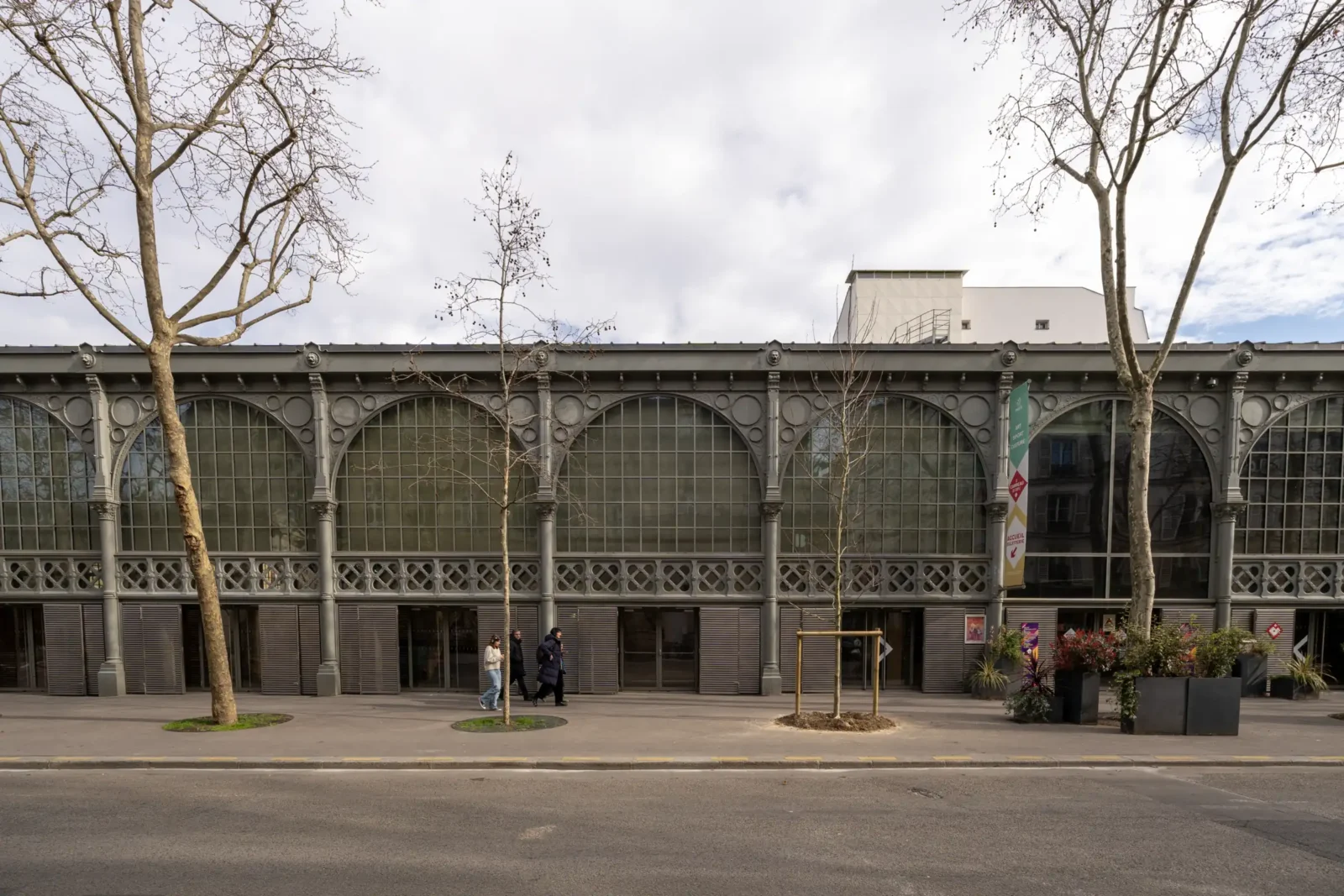 La façade métallique du Carreau du Temple à Paris devant des arbres sans feuilles.