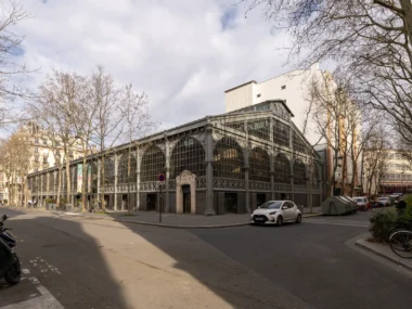 La façade métallique du Carreau du Temple se dresse dans une rue de Paris.