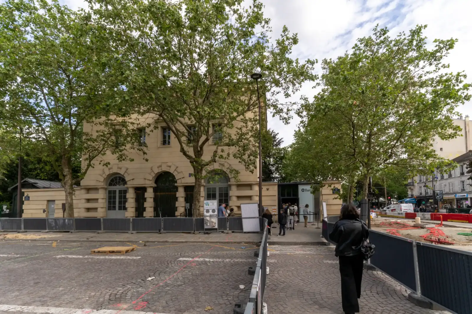 Vue extérieure de l'entrée des catacombes de Paris avec des visiteurs et des arbres.