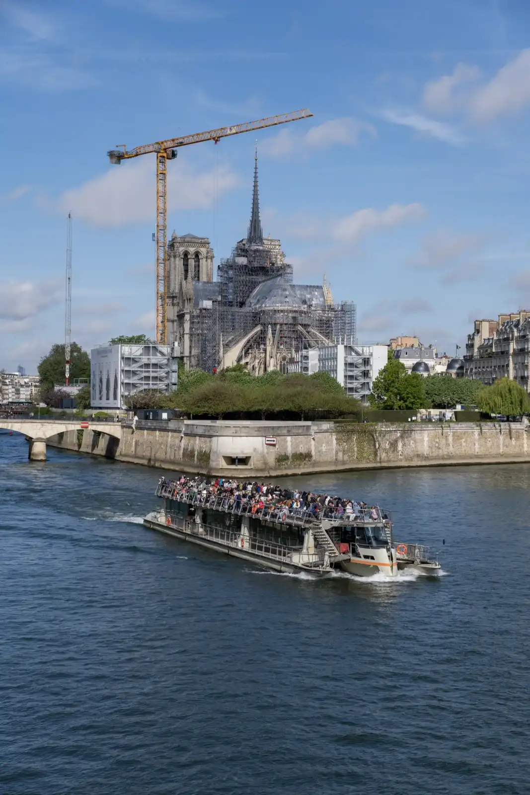 Un bateau de touristes navigue sur la Seine devant la cathédrale Notre-Dame en travaux.