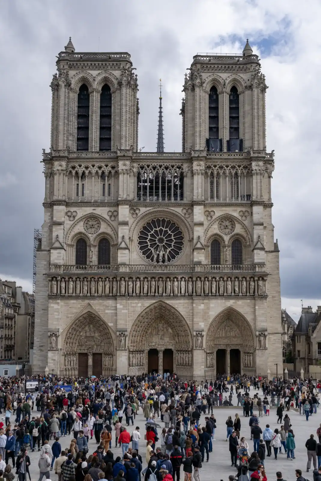 La cathédrale Notre-Dame de Paris se dresse majestueusement devant une foule de touristes nombreux.