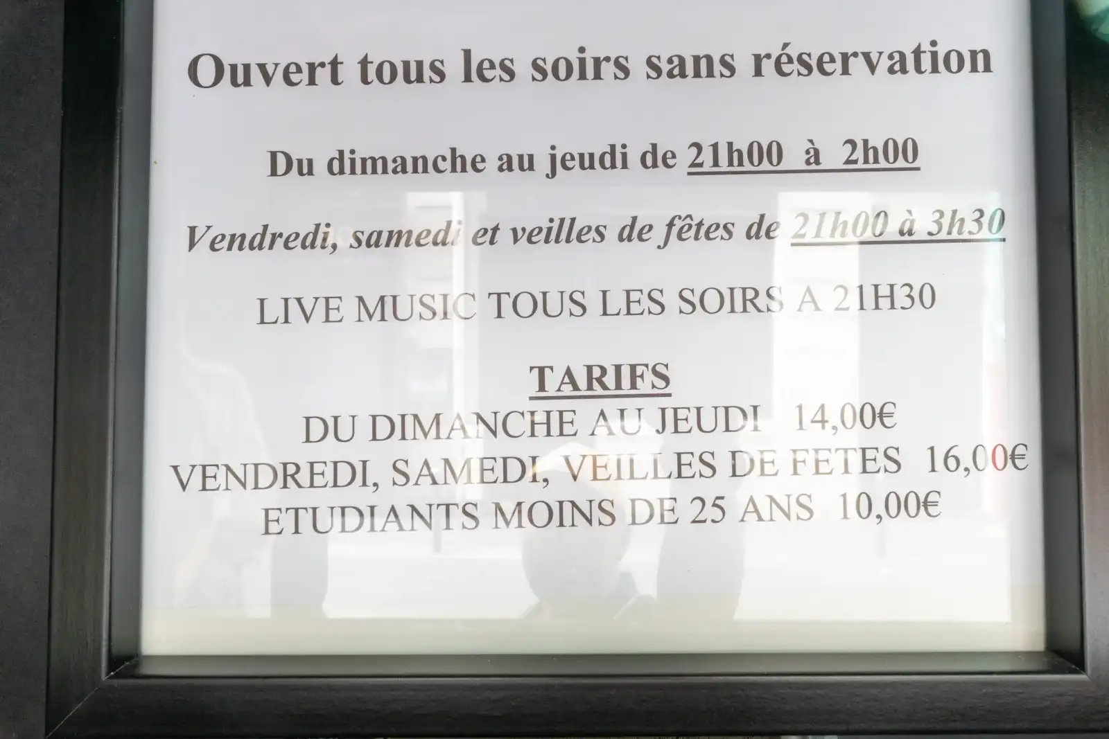 Panneau encadré indiquant les horaires et tarifs de la célèbre salle de jazz parisienne.