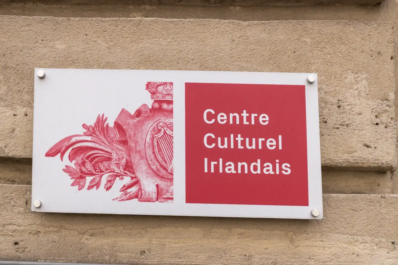 Une plaque blanche et rouge fixe l'inscription Centre Culturel Irlandais sur un mur beige.