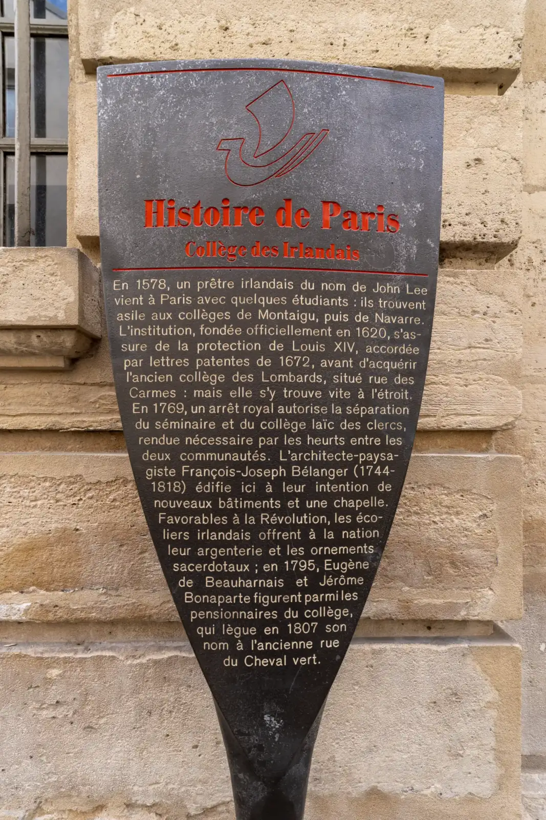 Un panneau noir Histoire de Paris fixé sur un mur en pierre calcaire.