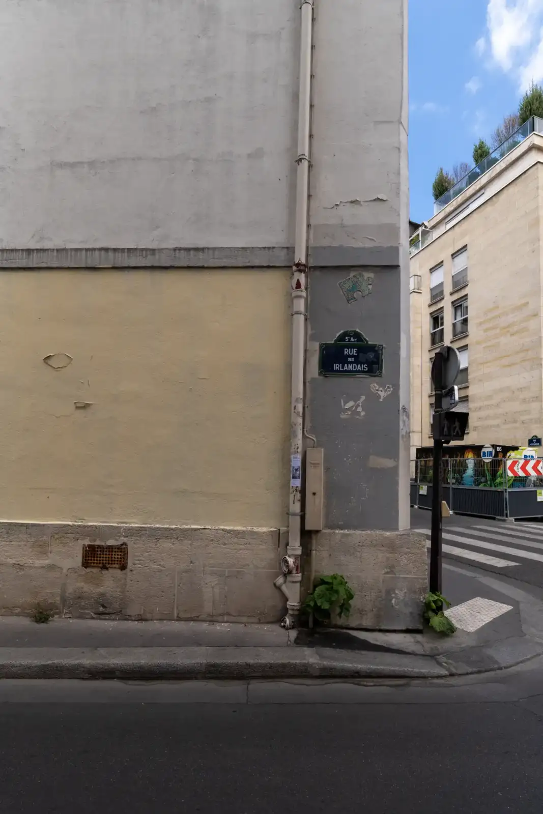 Plaque de rue bleue sur un mur gris à Paris, près d'un passage piéton.