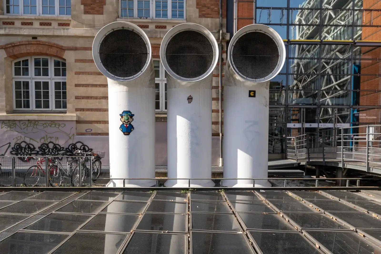 Trois grands conduits blancs ornés de mosaïques devant le centre Pompidou à Paris.