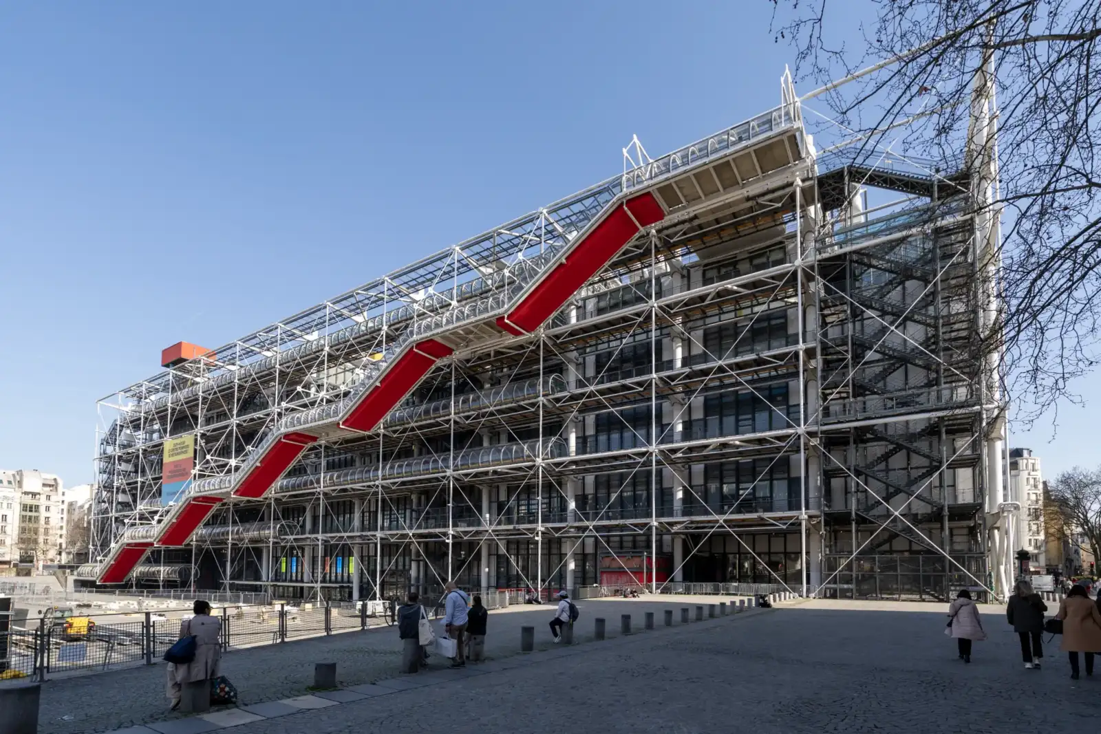 Le Centre Pompidou à Paris présente une architecture industrielle moderne avec un escalier rouge.