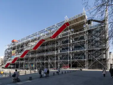 Le Centre Pompidou à Paris présente une architecture industrielle moderne avec un escalier rouge.
