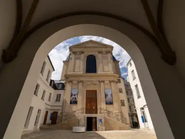 La façade claire de la chapelle se dévoile à travers une grande arche voûtée en pierre.