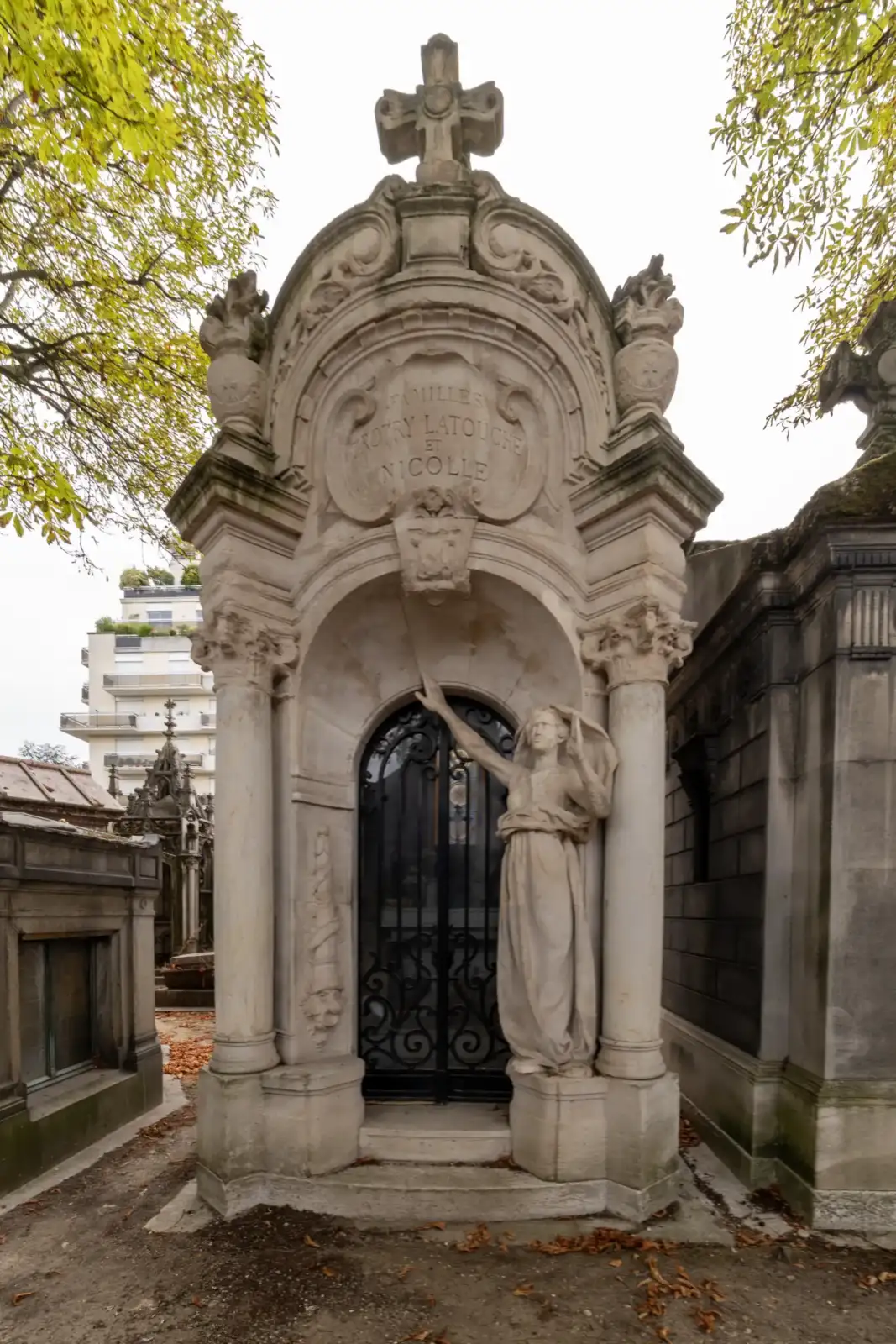 Un grand mausolée en pierre blanche surmonté d une croix dans un cimetière.