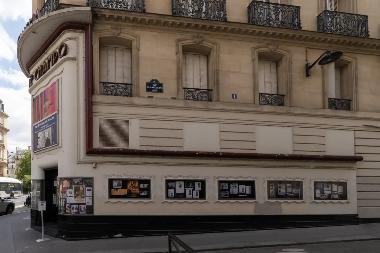 Une façade classique parisienne abrite l'entrée du cinéma Le Champo avec des affiches de films.