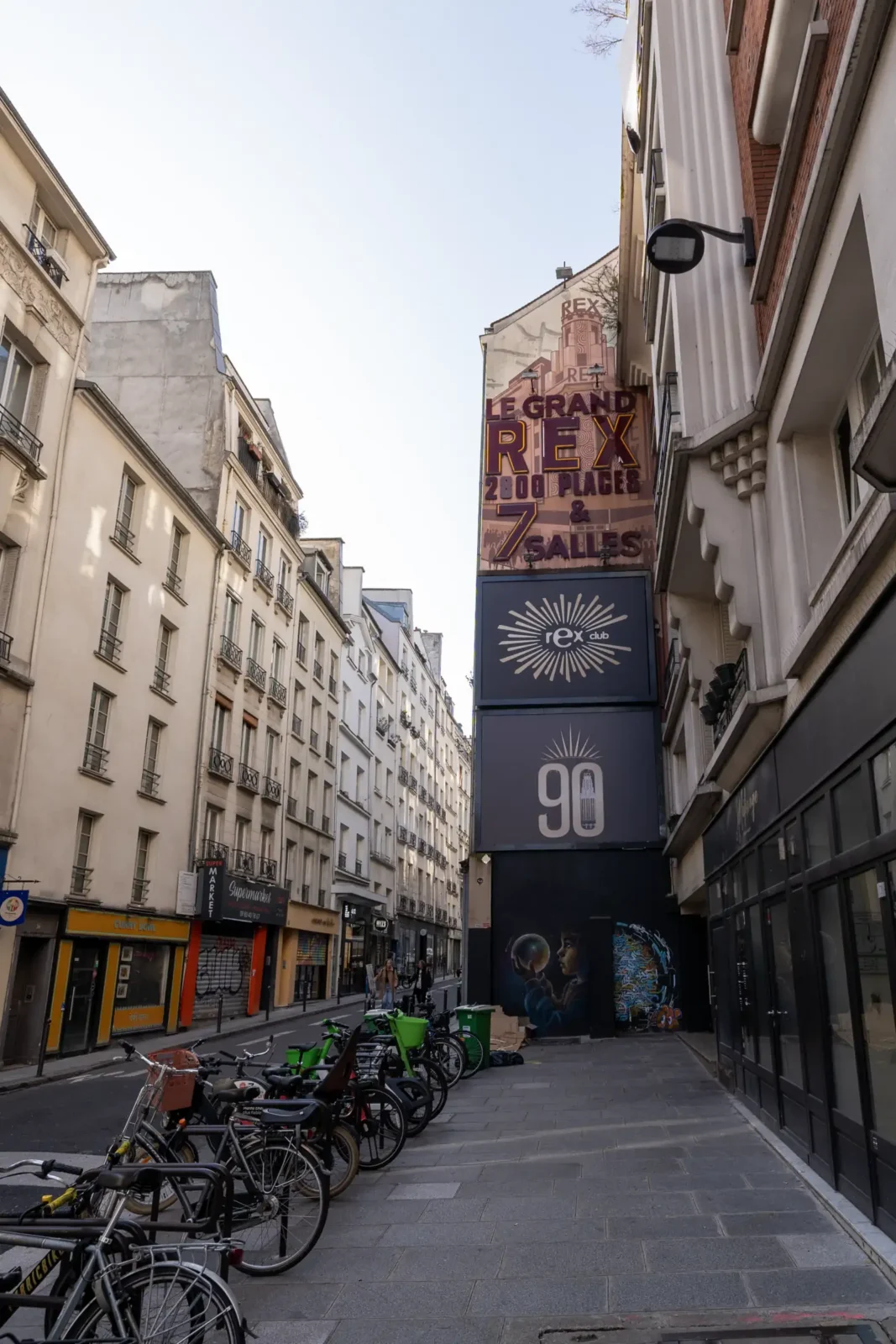 Façade du cinéma Le Grand Rex à Paris avec des vélos garés en rue.