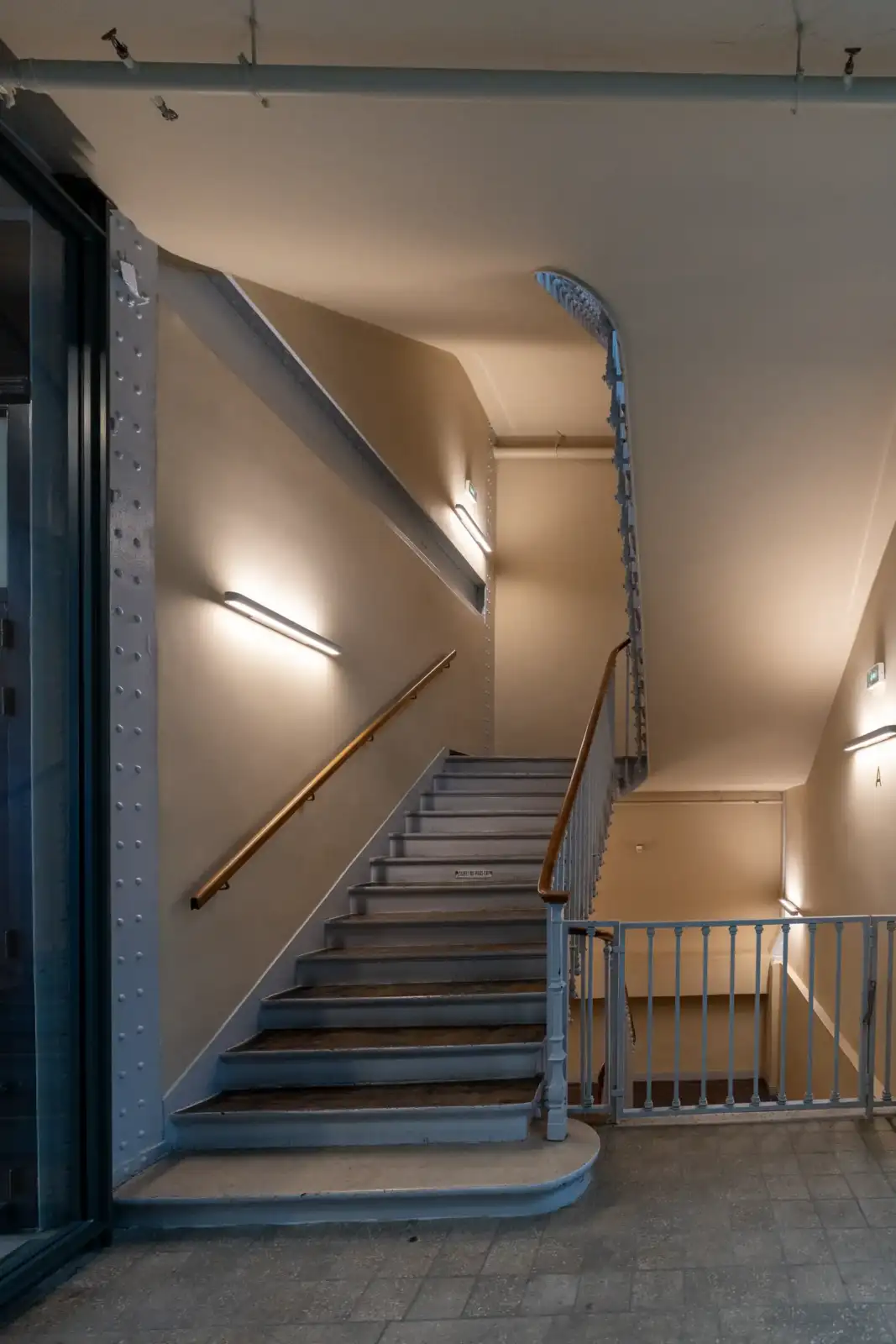 Vue de l'entrée et de l'escalier intérieur lumineux d'un bâtiment parisien.