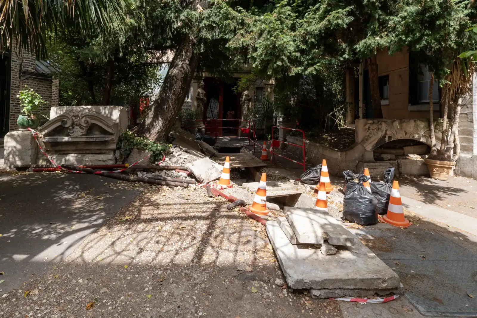 Une allée arborée de La Ruche à Paris présente des travaux entourés de cônes orange.