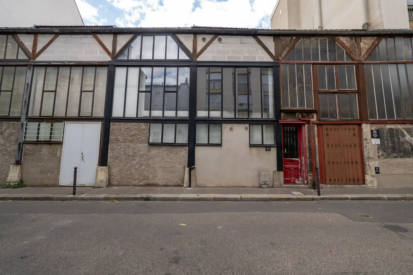 Une façade d atelier ancienne avec de grandes verrières et des portes colorées.