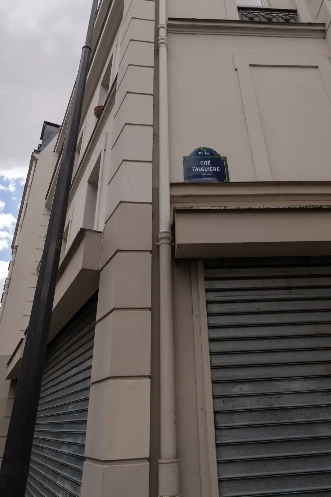 Plaque de rue bleue indiquant Cité Falguière sur un immeuble beige à Paris.